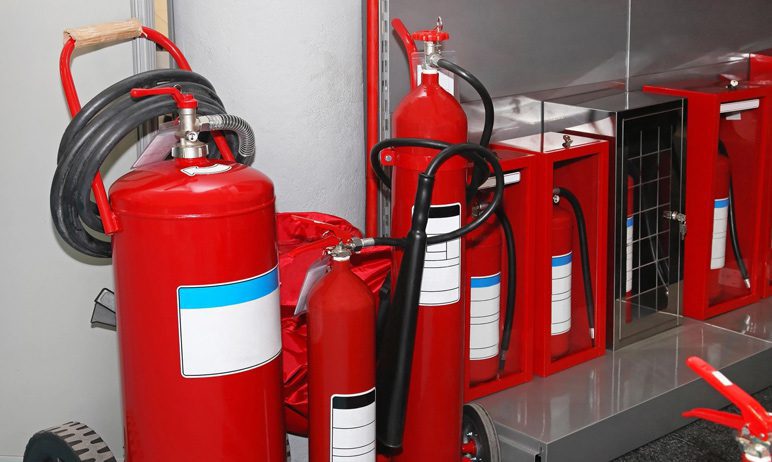 A group of red fire extinguishers sitting next to each other.