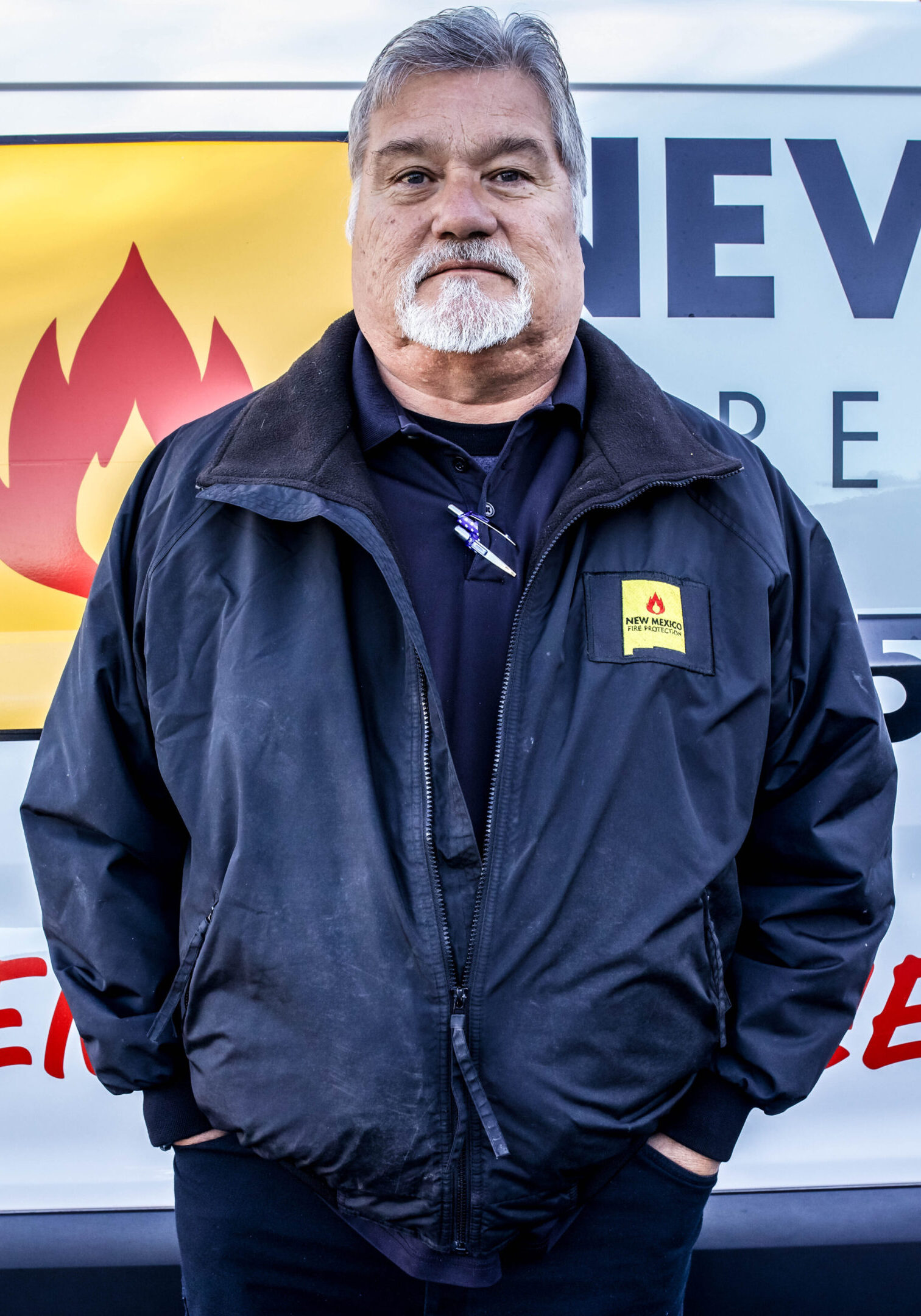 A man in black jacket standing next to fire hydrant.